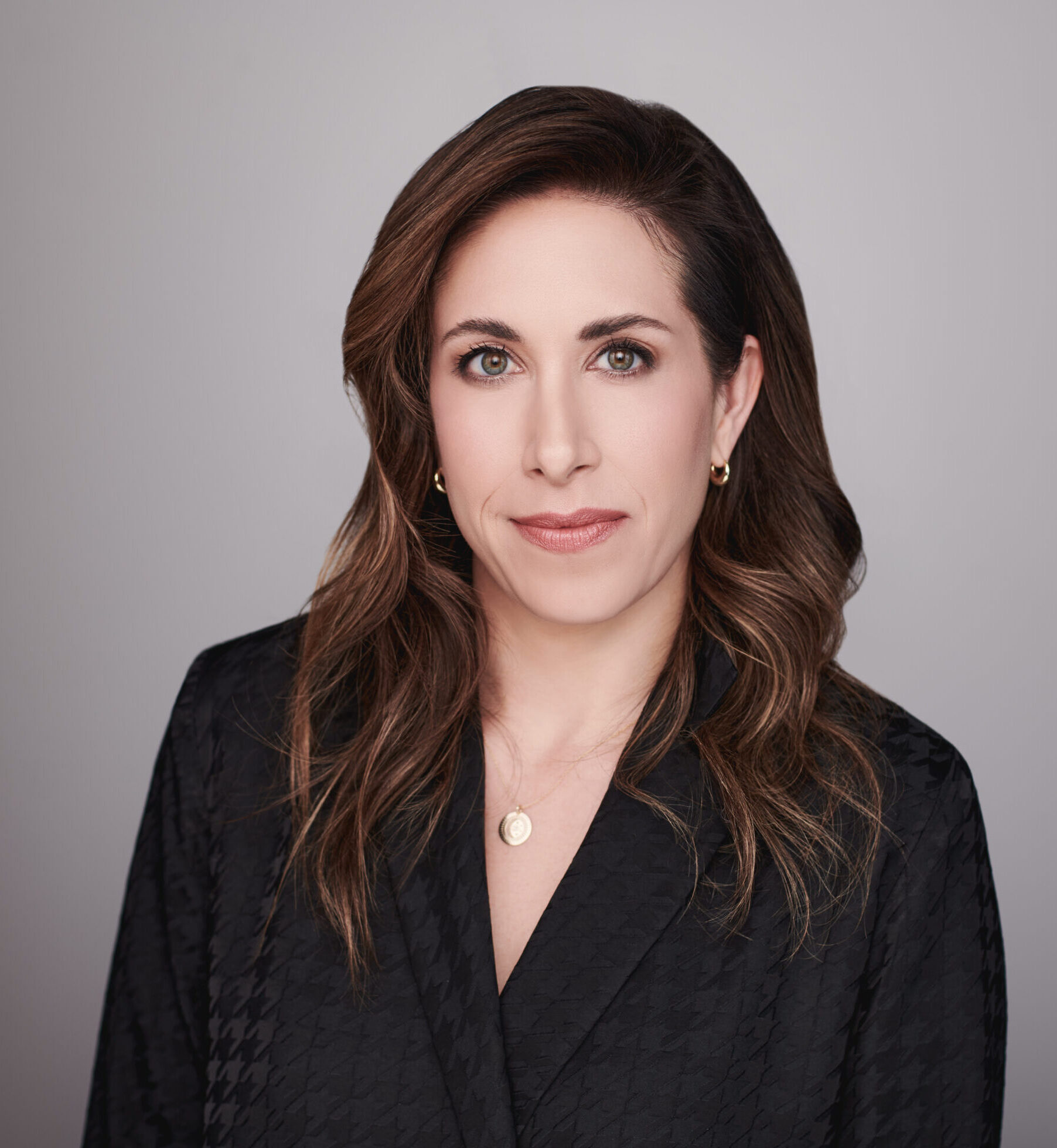 A woman with brown hair looks at the camera.